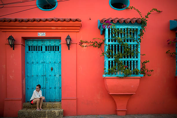 Woman sits on door step in Cartagena, Colombia The classic city of Cartagena is full of colonial Spanish architecture, which lives on today in modern Colombian society.  A caucasian woman sits on the steps to the house. cartagena colombia stock pictures, royalty-free photos & images