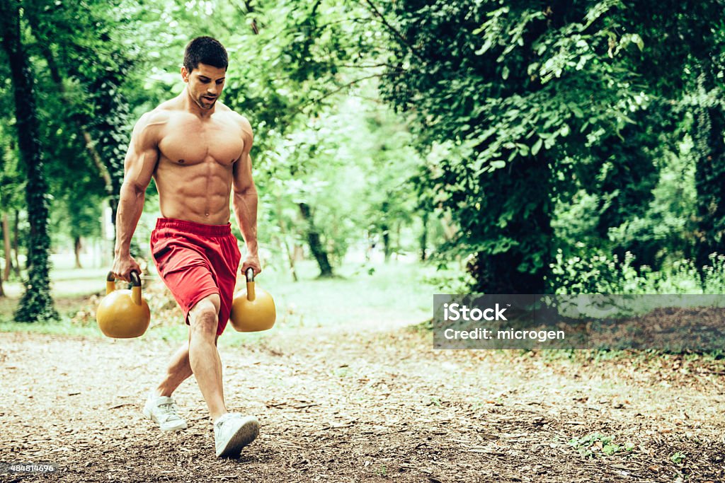 gym lunges with kettle bells Muscular athlete male walking with kettle bells, doing  lunges Kettlebell Stock Photo