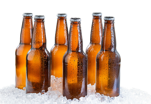 Six pack of bottled beer with drops and ice isolated on white background