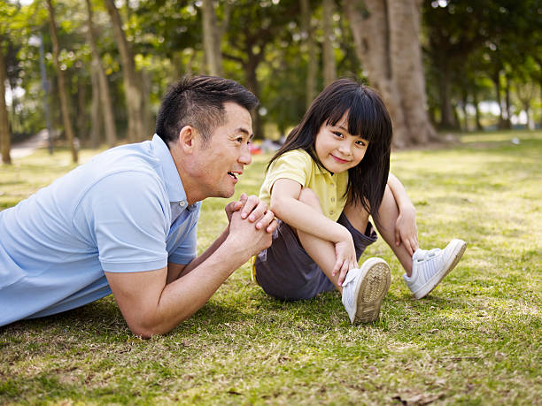 istock asian father and daughter relaxing in park 484824774