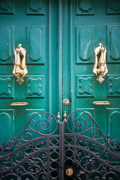 istock Old wooden door, beautiful knockers, cast iron gate. 484825182