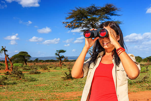 istock Young woman is looking through a binoculars during safari 484830980