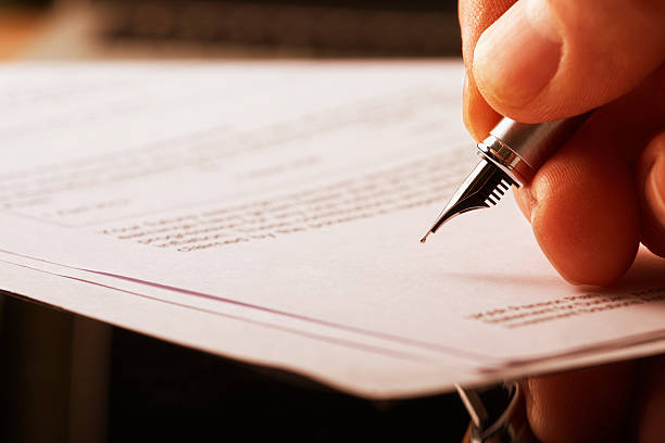 Fountain Pen Signature. A hand holding a fountain pen and about to sign a letter. Styling and small amount of grain applied. treaty stock pictures, royalty-free photos & images