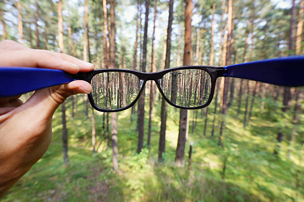 istock eyeglasses in the hand over blurred forest background 484836964