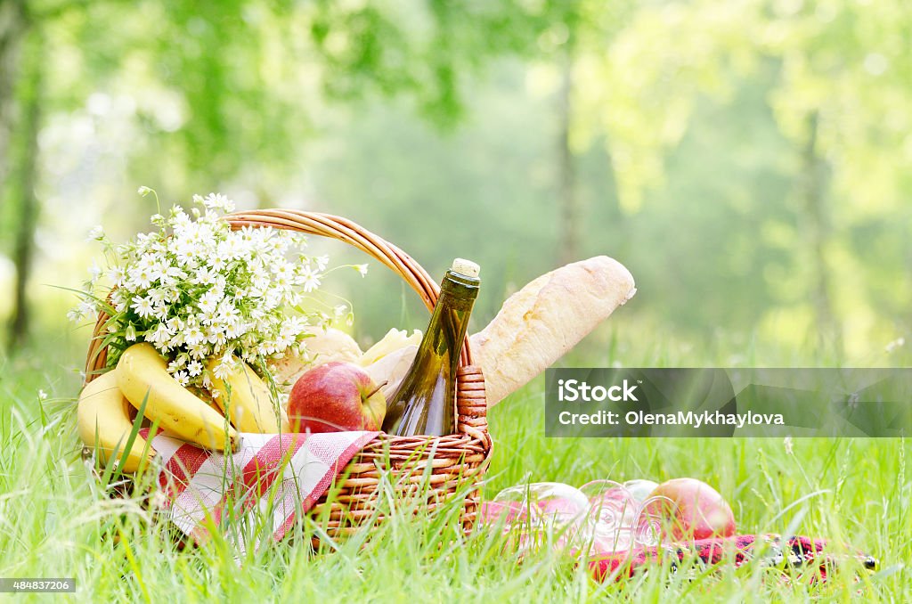 Picnic basket Picnic basket with apples bananas cheese and wine on green grass. Space for text 2015 Stock Photo