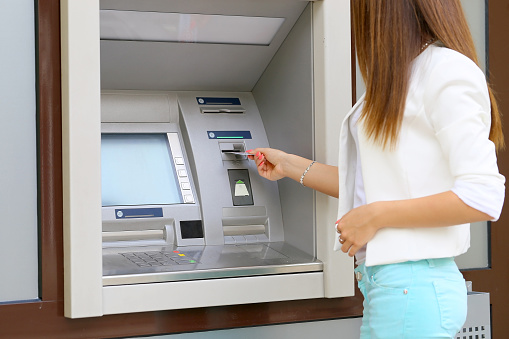 young woman inserting a credit card to ATM