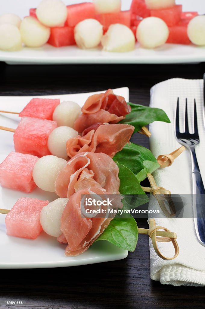 ham with melon and watermelon Appetizer of ham with melon and watermelon and basil on a skewer 2015 Stock Photo