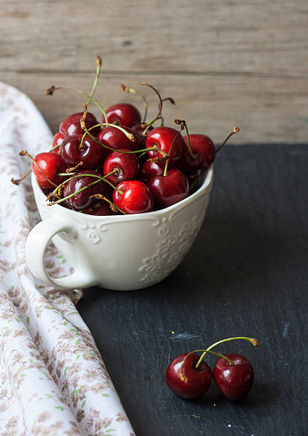 istock Cherries in a cup on a wooden background 484841936
