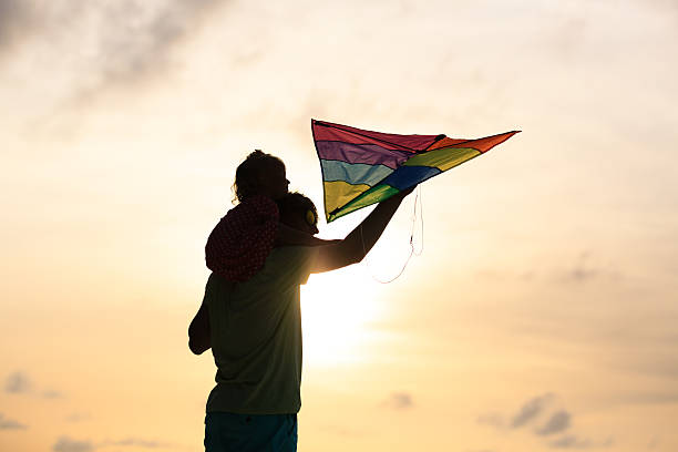 istock father and little daughter flying kite at sunset 484844158