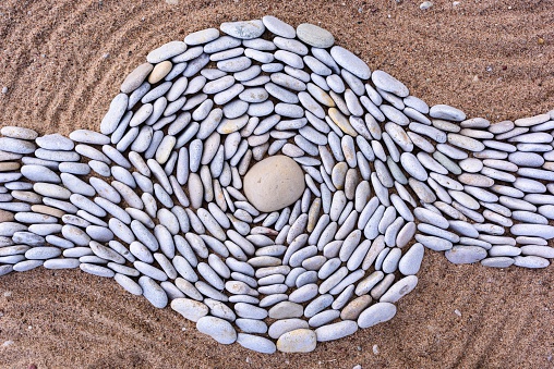 Twisting of stones on a sandy beach.