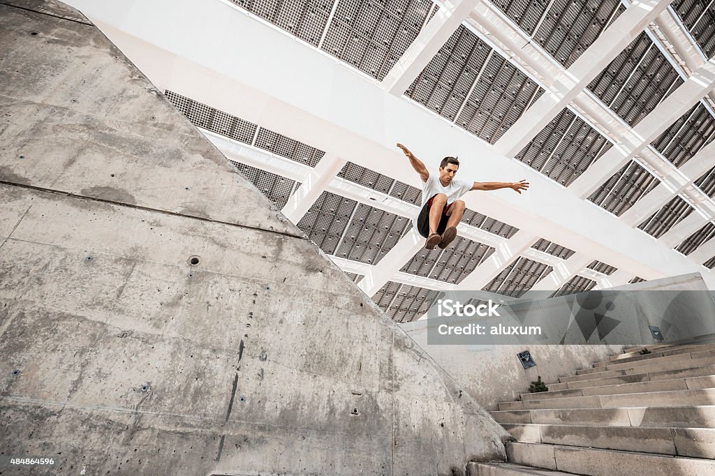 Man jumping doing urban parkour Young man practicing parkour in the city Free Running Stock Photo