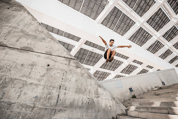 Man jumping doing urban parkour Young man practicing parkour in the city acrobatic activity stock pictures, royalty-free photos & images