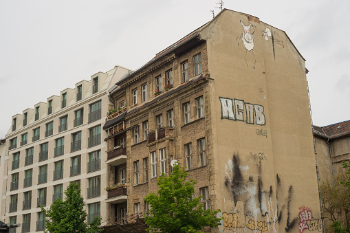 Rotten house with grafitti besides a new apartment house in Berlin (Germany)