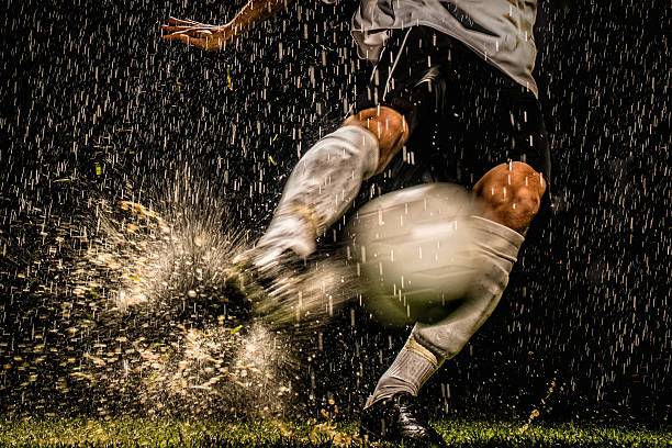 Soccer Player in Action Soccer player kicks ball with full power in the rain at night. kicking photos stock pictures, royalty-free photos & images