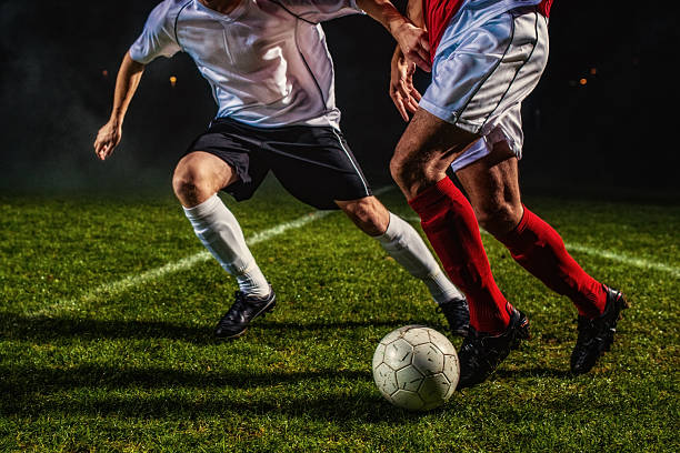 Soccer Players in Action Two soccer players challenging for the ball, low angle view. defending sport photos stock pictures, royalty-free photos & images