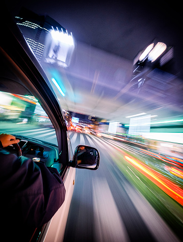 A car drives through the brightly lit Shibuya area of Tokyo, Japan at night. Taken with a remote mounted camera on the exterior of the moving car.