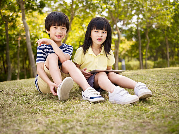istock beautiful asian children sitting on grass 484875436