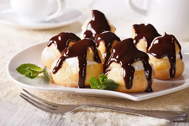 Delicious eclairs with cream and chocolate frosting on a plate. horizontal