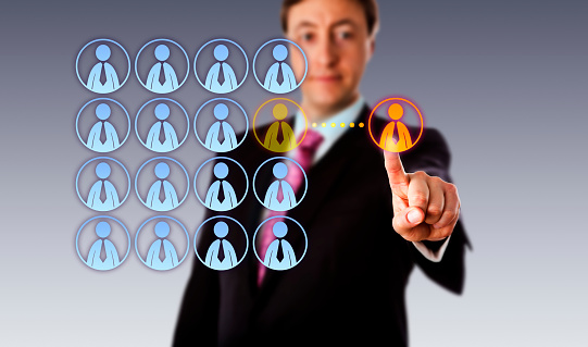 Smiling manager is touching a single male white collar worker icon outside an organized group of male employee icons. Business metaphor for outsourcing, crowdsourcing, hiring and contracting.