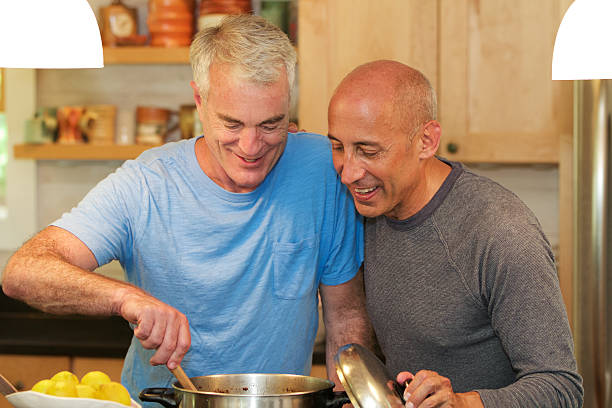 Senior Gay Male Couple Cooking and Smiling in Kitchen stock photo