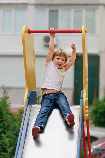 istock girl riding down the slide on the Playground 484906262