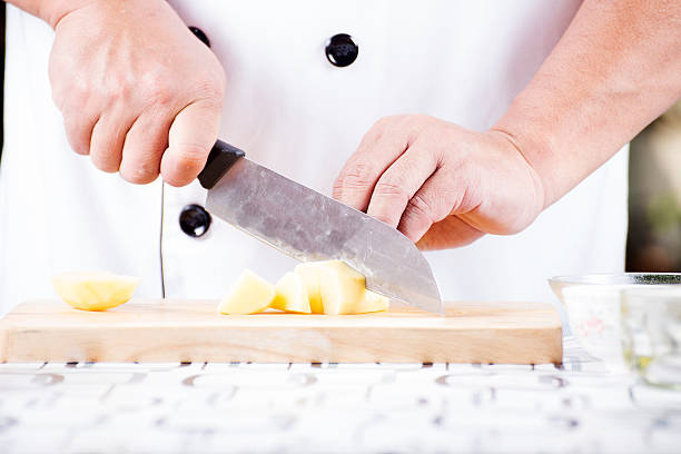 istock Chef cutting Potato on wooden broad 484922292