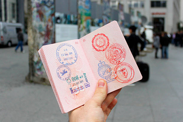 Passport with stamps. Berlin, Germany - September 22, 2011: Man holding open passport with stamps of the Cold War at the background of fragments of the Berlin Wall. soldier on the wall stock pictures, royalty-free photos & images