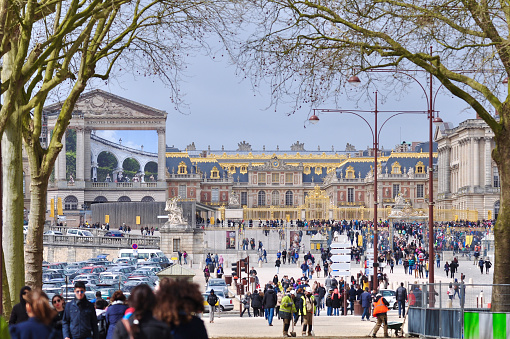 Versailles, France - March 31, 2015: Many tourists are walking toward a long queue to enter Versailles Palace, France.