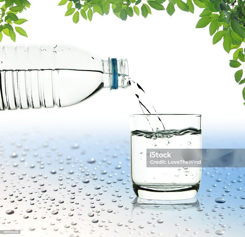 Drinking water is poured from a bottle into a glass Drinking water is poured from a bottle into a glass with clipping pathDrinking water is poured from a bottle into a glassDrinking water is poured from a bottle into a glass 2015 Stock Photo