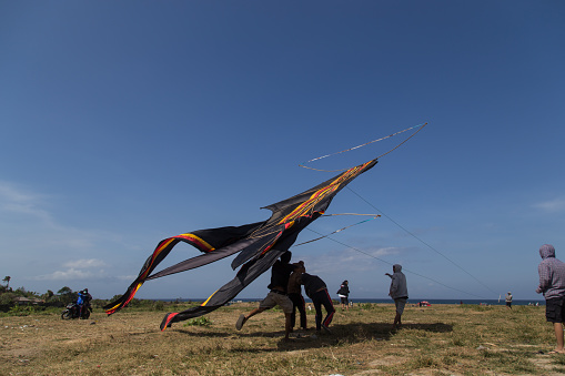 Sanur, Bali, Indonesia - July 19, 2015: A group of people is starting a gigantic kite at Sanur Beach.