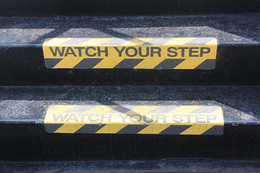 Yellow and black warning sign on stairs stating 