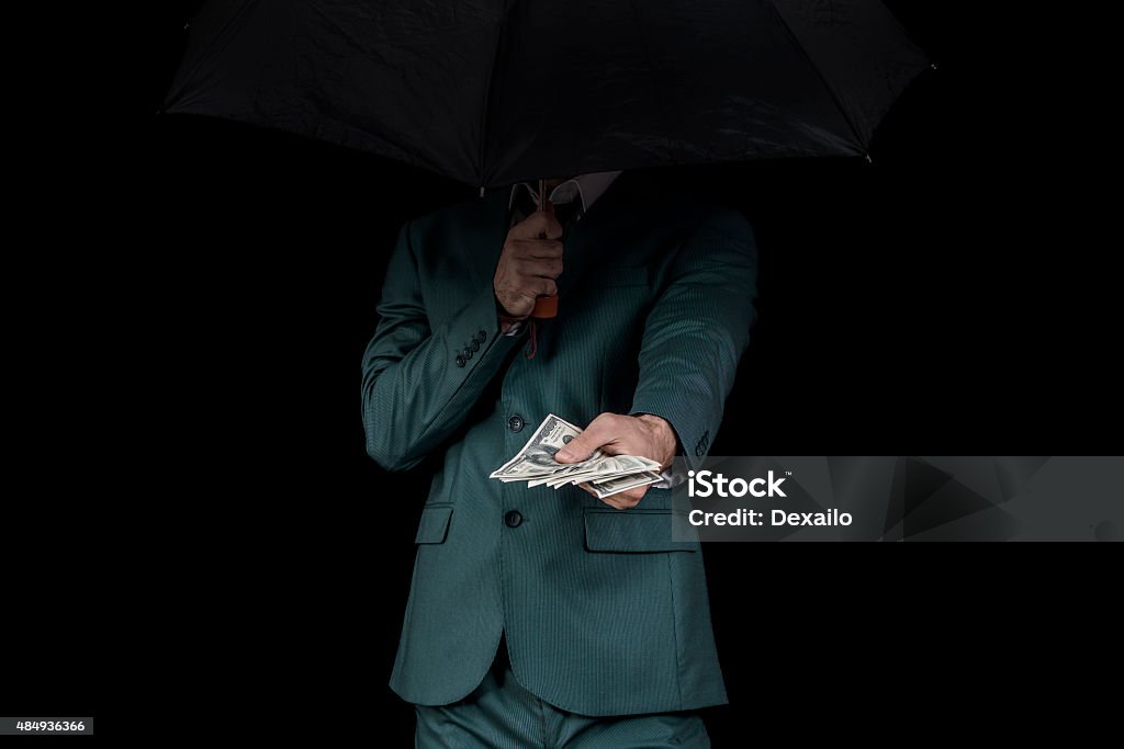Corruption man Man hiding behind an umbrella, offering money Organized Crime Stock Photo