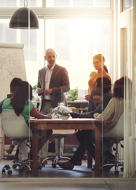 Sharing his business acumen Shot of a group of coworkers in a boardroom meetinghttp://195.154.178.81/DATA/i_collage/pi/shoots/784885.jpg workplace diversity vertical stock pictures, royalty-free photos & images