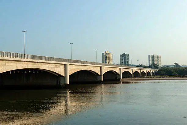 Arched bridge over umgeni river with apartment buildings in background in Durban, South Africa