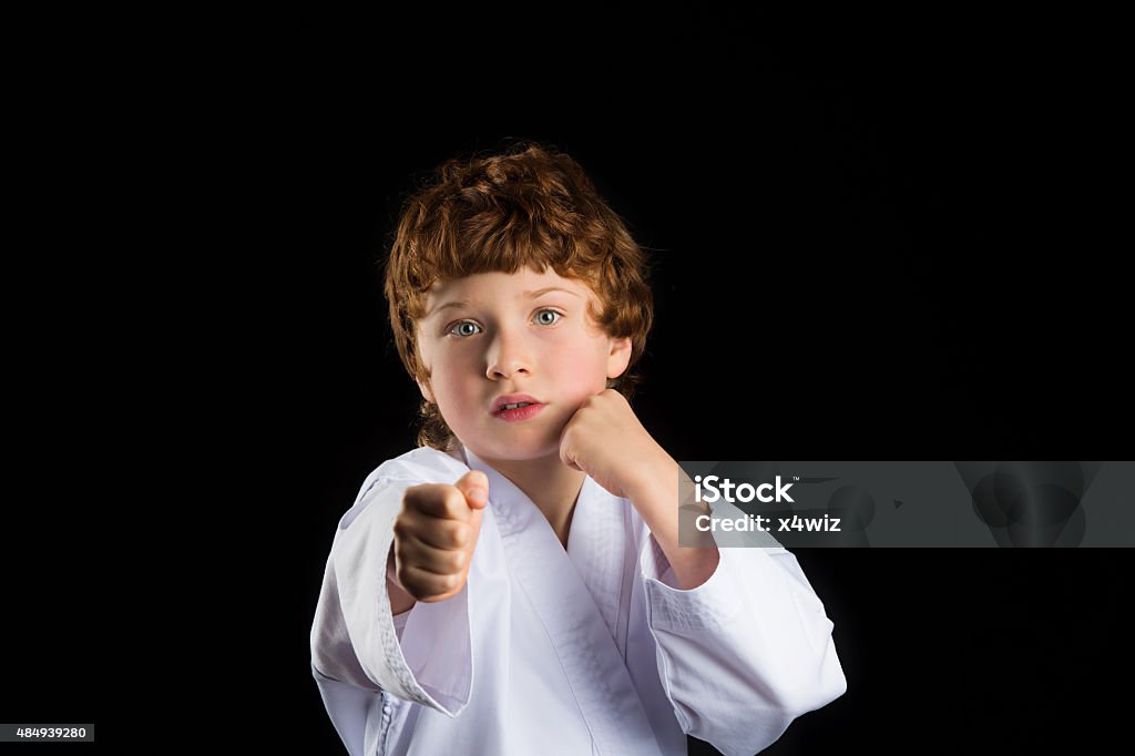 Karate boy in white kimono isolated on black background Redhead caucasian karate boy in white kimono isolated on black background 2015 Stock Photo