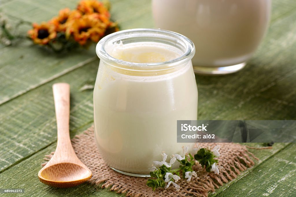 white yogurt in glass jar white yogurt in glass jar on green table for breakfast 2015 Stock Photo