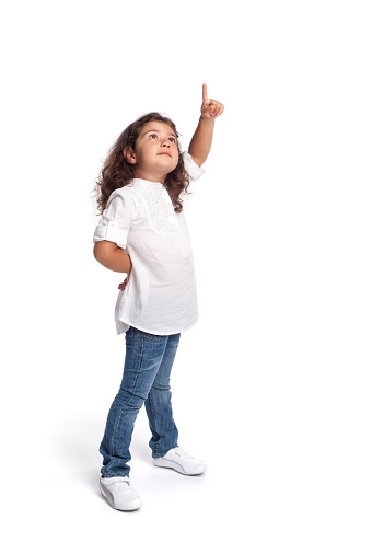 Full length portrait of a happy little girl on white background pointing