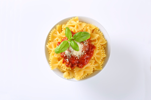 bowl of farfalle pasta with tomato sauce and grated parmesan on white background