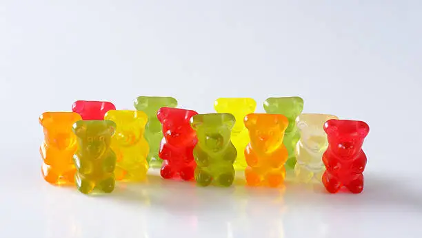 group of multicolored gummy bears standing on white background