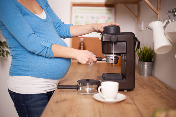 Pregnant woman making coffee stock photo