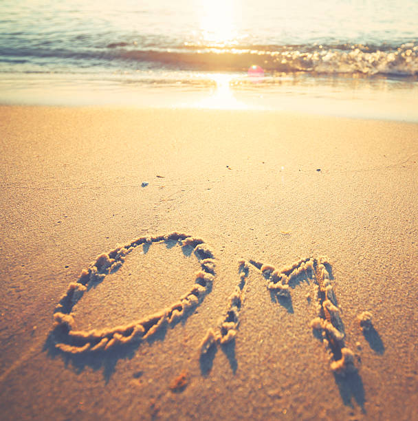 istock Om letter in the sand by the ocean 484955304