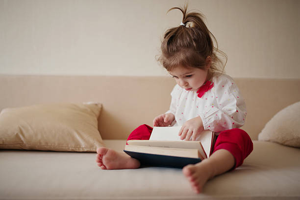 istock little girl reading book at home 484967736