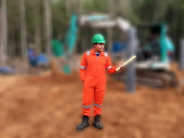 Thai construction site worker wearing high visibility safety jacket standing and hold paper