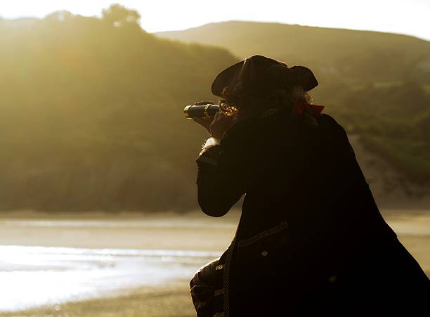 istock silhouette of pirate crouching on rocks looking through his telescope 484968774