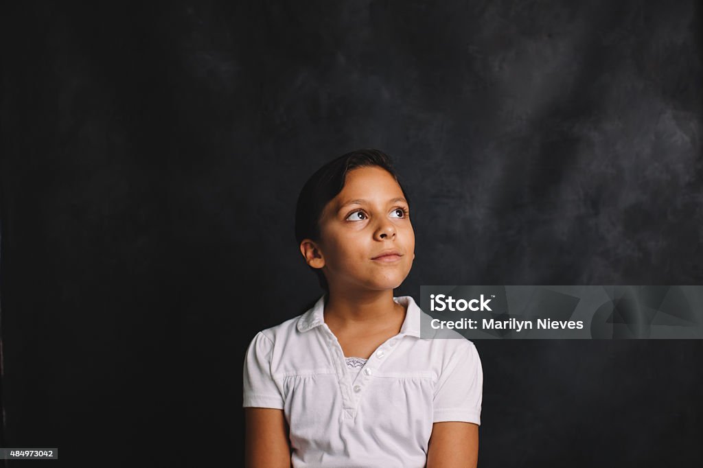 young female student sitting in front of blank blackboard Student series. Child Stock Photo