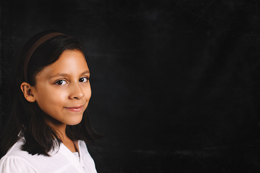Student series. Young girl smiling in front of a chalk board. Copy space.