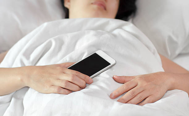istock Woman sleeping in bed and holding a mobile phone. 484973300