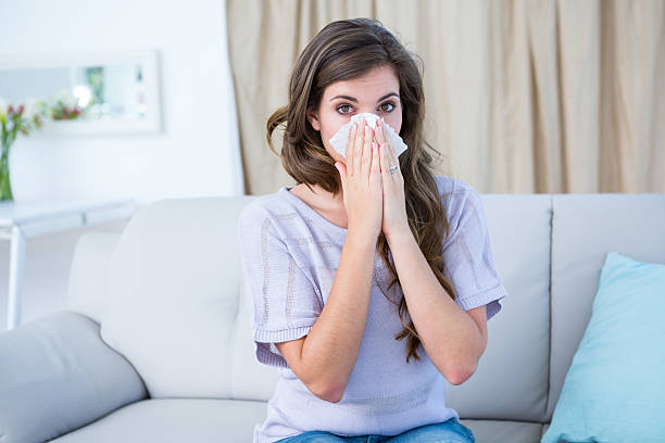 istock Sick woman blowing her nose looking at camera 484977386