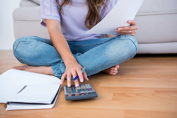 istock Woman calculating receipts lying on the floor 484978918