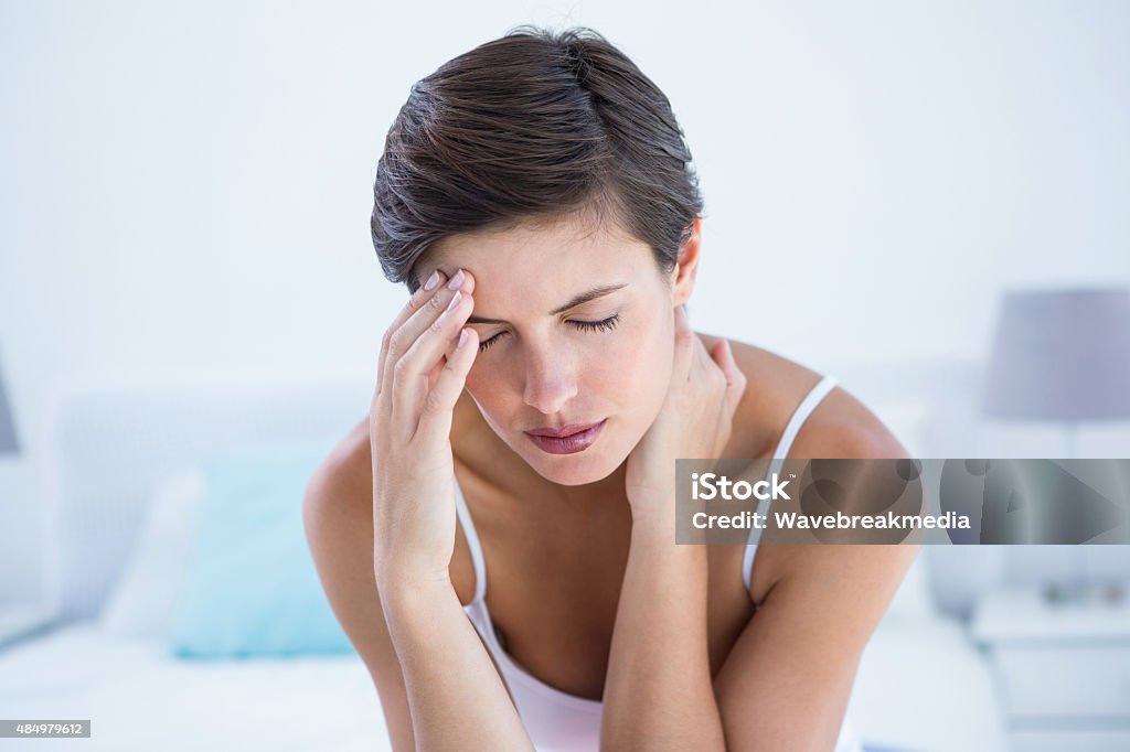 Beautiful brunette suffering from head ache Beautiful brunette suffering from head ache at home in the bedroom  20-29 Years Stock Photo